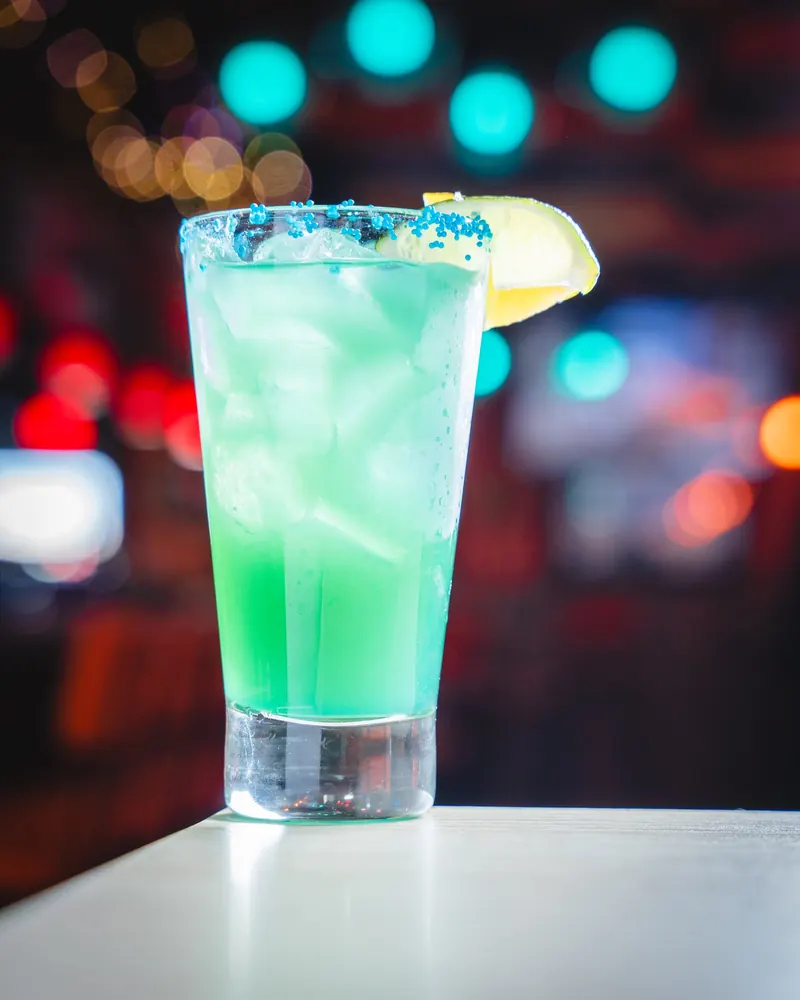 A blue cocktail with a lime wheel