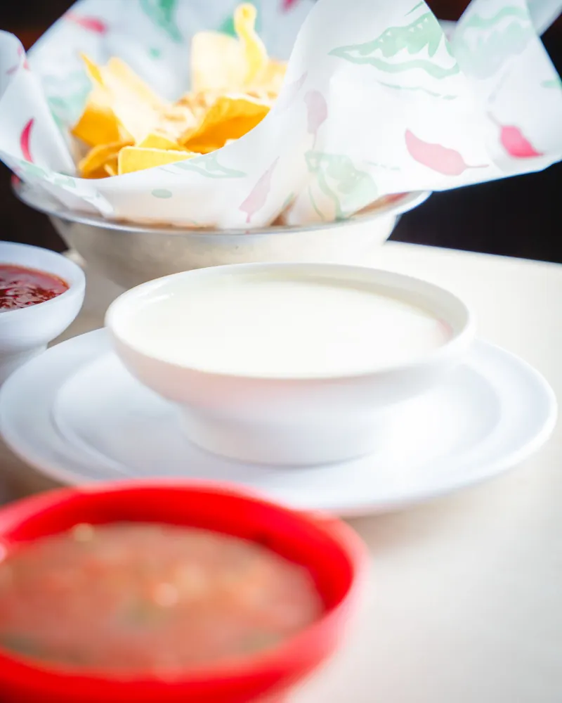A bowl of cheese dip with chips and salsa