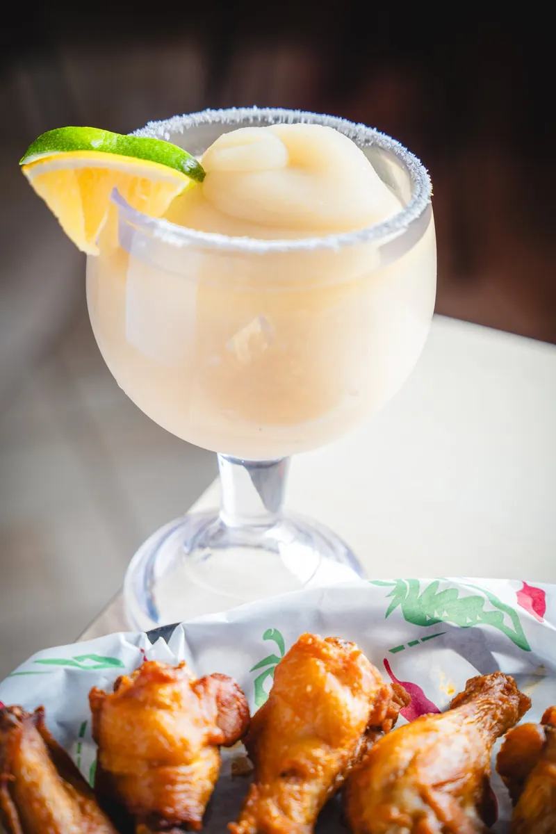 A jumbo frozen margarita next to a basket of wings