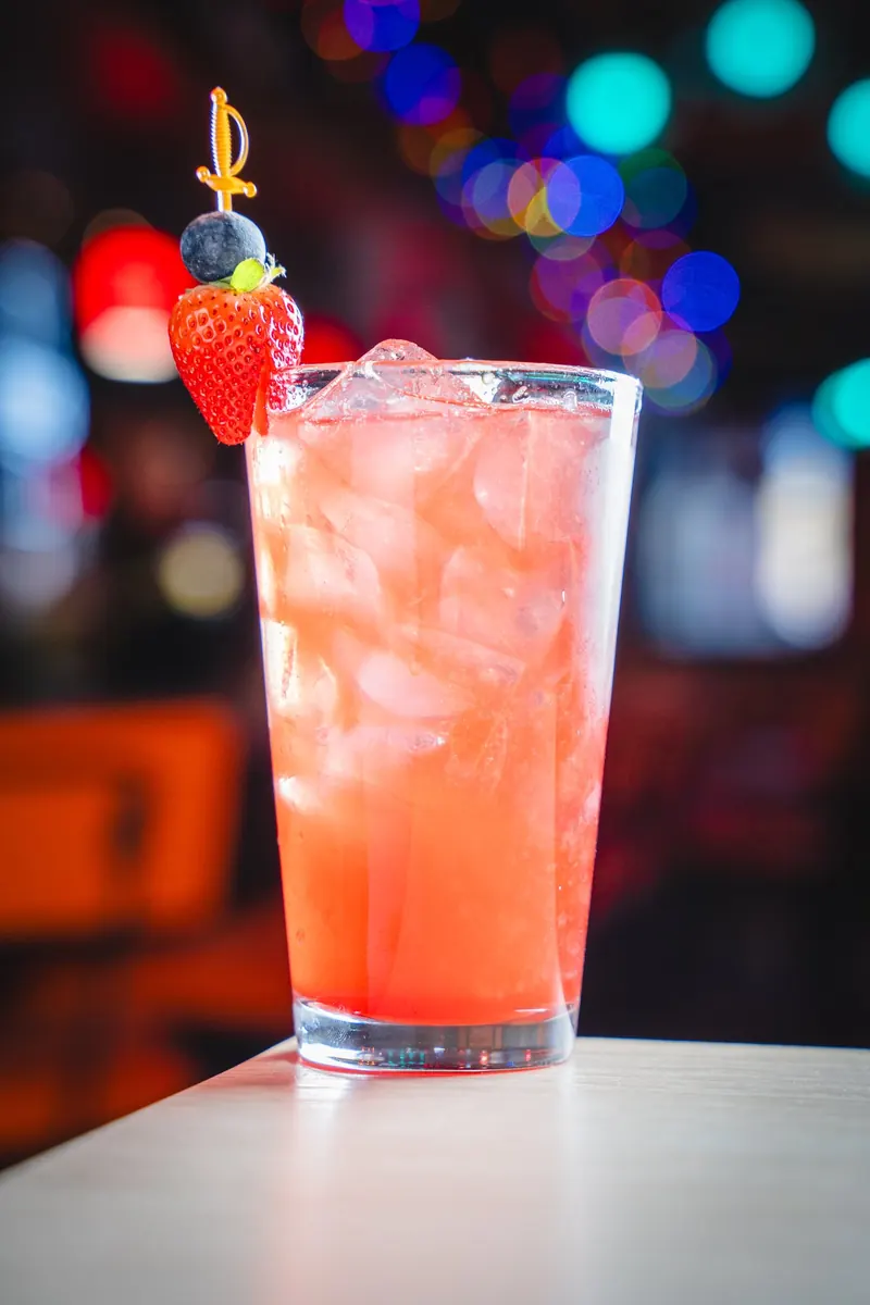 A red berry cocktail with a strawberry garnish